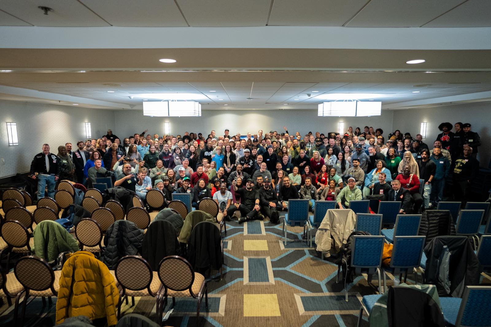 Attendees gather for a group photograph at the front of a hotel ballroom during a SubTo member meetup.