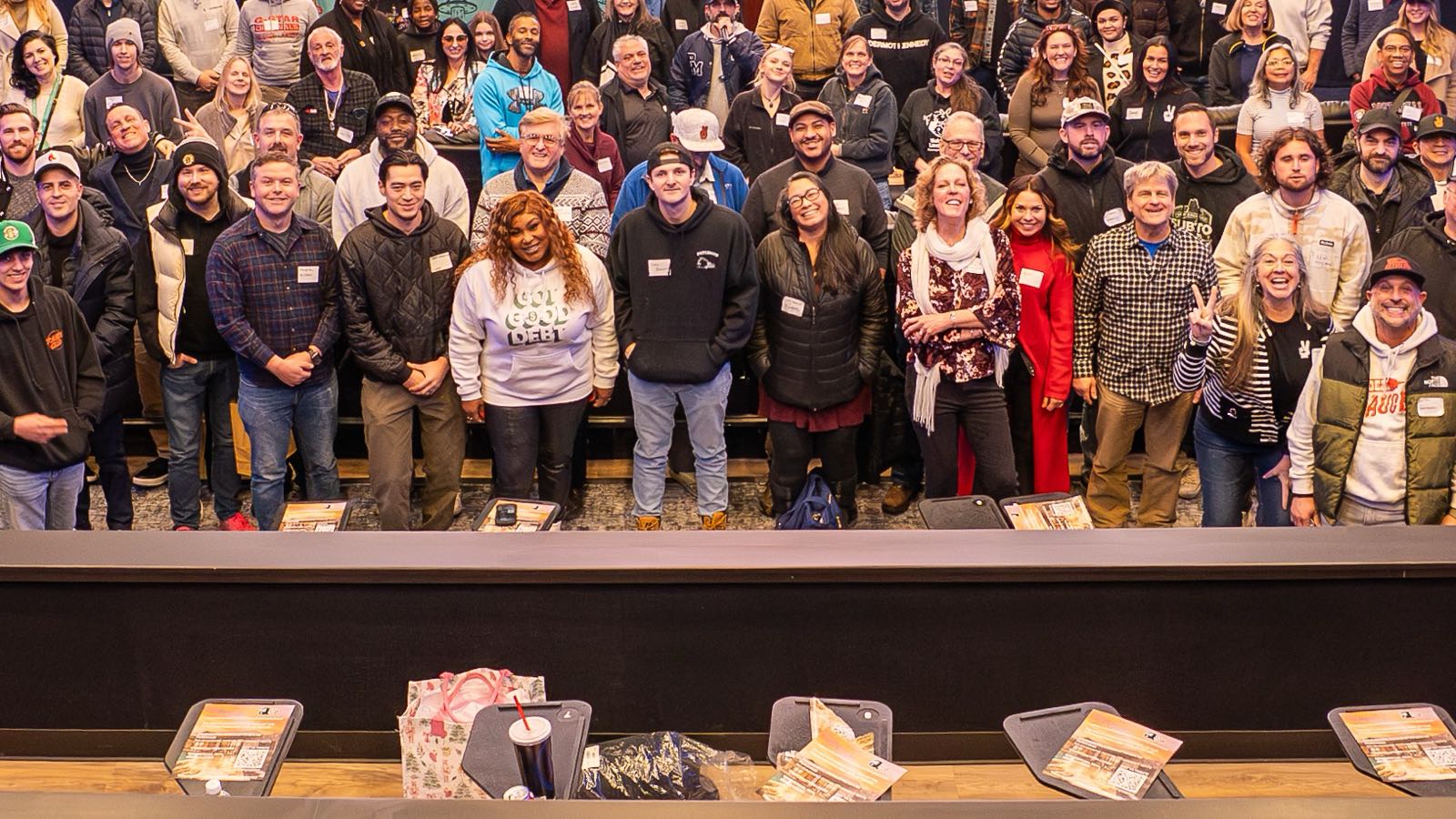 Attendees standing in rows in a screening room at a SubTo community session, with printed handouts along the counter in front of them. Archive photograph, not this meetup.
